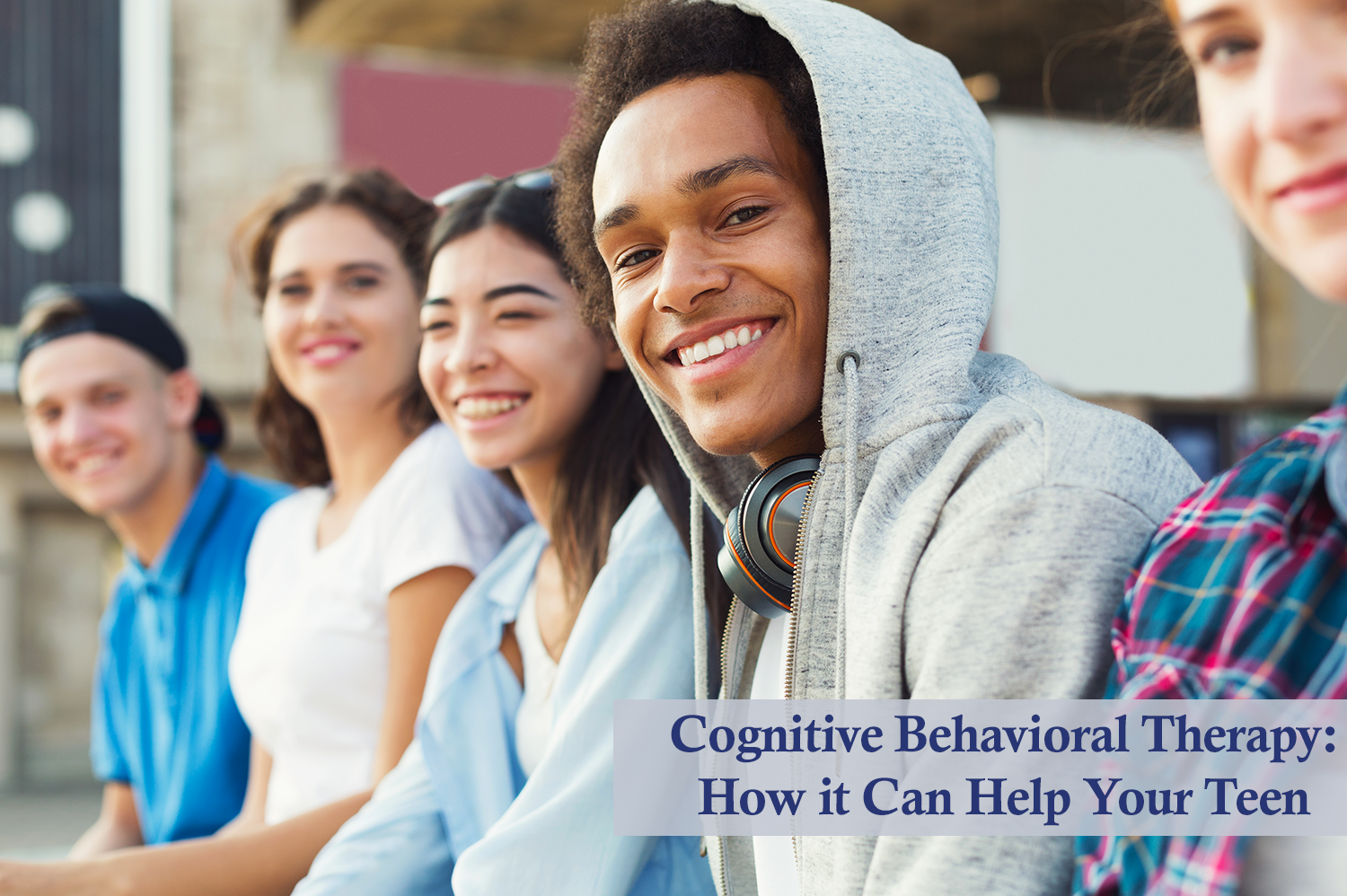 Teens sitting in a row, smiling at the camera after their cognitive behavioral therapy session.