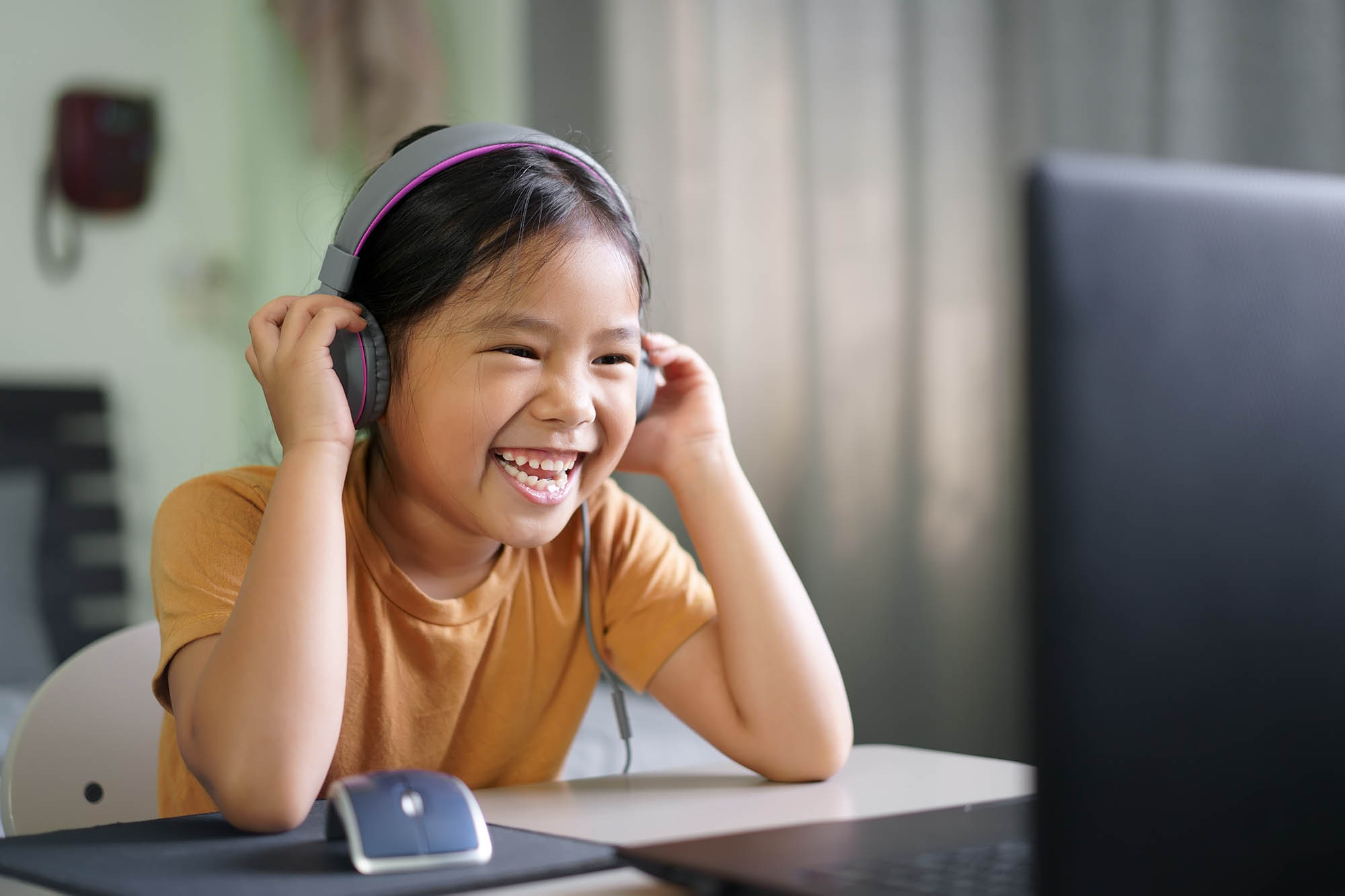 Happy girl speaking with a therapist on computer wearing headphones